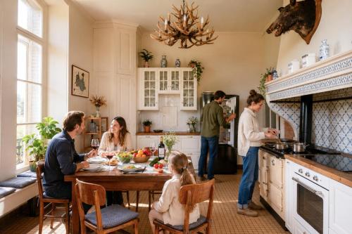 a group of people sitting around a table in a kitchen at Private Château with sauna, hot tub & 4ha park - Château Guillermo in La Moncelle
