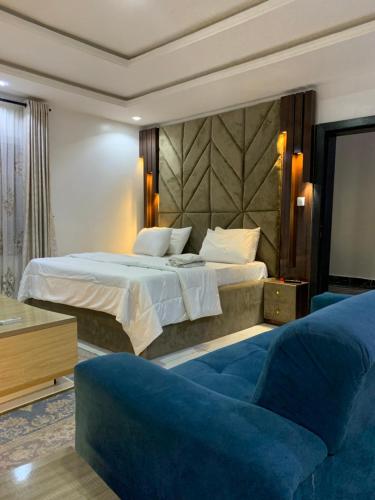 a bedroom with a large bed and a blue couch at PrimeNest Apartment in Lekki