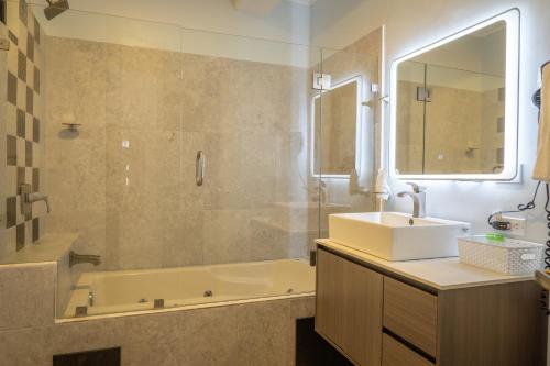 a bathroom with a tub and a sink and a mirror at Hotel Luckys in San Isidro de El General