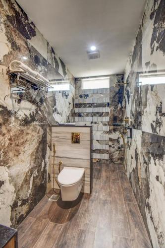 a bathroom with a toilet and a stone wall at The White Castle Hotel in Mysore