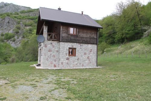 a small house in a field with a hill at BB Etno House in Kolašin