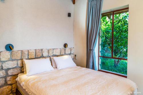 a bedroom with a bed with a stone wall and a window at Red and White אדום לבן in Amirim