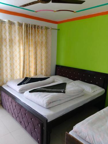 a bed in a room with a green wall at Vinod Tourist Lodge in Gupta Kāshi