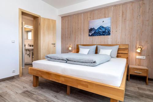 a bedroom with a large white bed with wooden walls at Ferienwohnung Kircher in Obermaiselstein