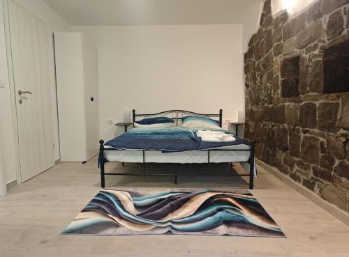 a bedroom with a bed and a stone wall at Sobe - Rooms NININ in Deskle