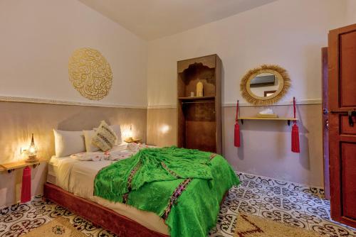 a bedroom with a bed with a green blanket on it at Riad Samir Oasis And Spa in Marrakesh