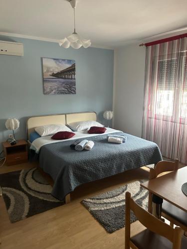 a bedroom with a bed with a blue blanket and a table at Guest House Ana in Zadar