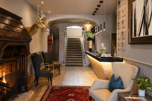 a living room with a fireplace and a staircase at Dunalastair Hotel Suites in Kinloch Rannoch