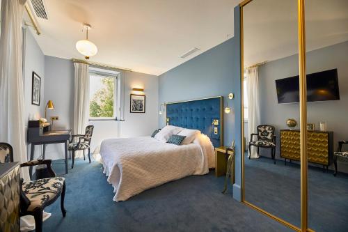 a bedroom with a bed and a desk and a mirror at Olivier Leflaive Hôtel Restaurants in Puligny-Montrachet