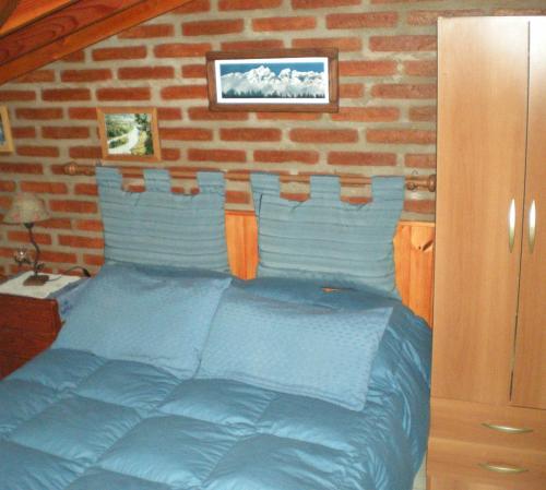 a bedroom with a blue bed with a brick wall at Cabañas Tunquelen in El Bolsón