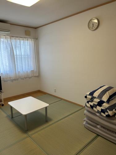 a room with a table and a clock on the wall at 小さなペンション Branchee in Kushimoto