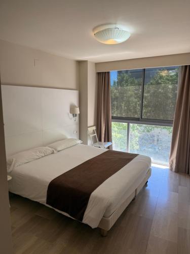 a bedroom with a large bed and a large window at Apartaments Peronel.la in Lleida