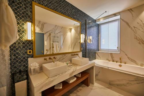 a bathroom with two sinks and a tub and a mirror at Olivier Leflaive Hôtel Restaurants in Puligny-Montrachet