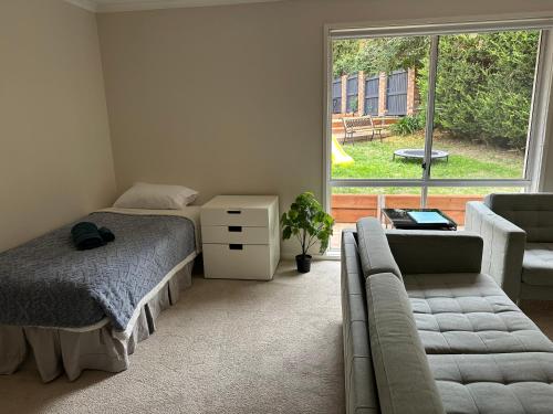 a bedroom with a bed and a couch and a window at Cozy Curtin Cottage in Lyons