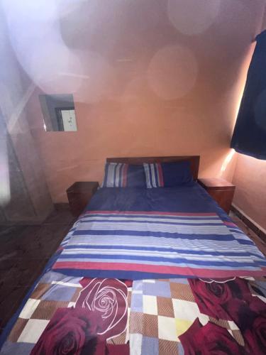 a bedroom with a bed with a colorful striped blanket at Sumanya guest house 3 in Sukuta
