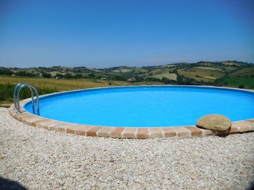 a large blue swimming pool with a brick curb at Casa Rustica mit privatem Pool zur alleinigen Nutzung in Corinaldo