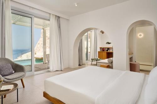 a white bedroom with a bed and a large window at Lilium Hotel Santorini in Fira
