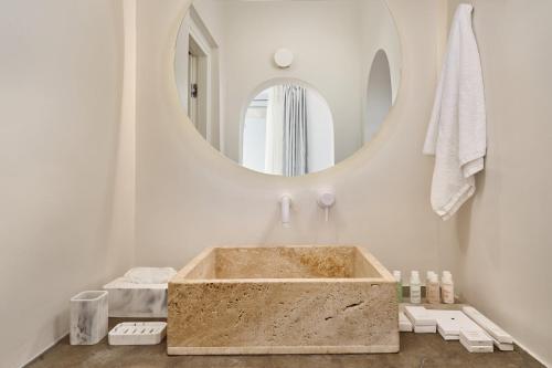 a bathroom with a stone tub in front of a mirror at Lilium Hotel Santorini in Fira