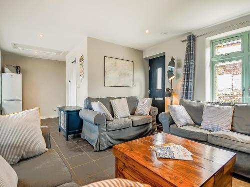 a living room with couches and a table at Greenrush Cottage in Blakeney