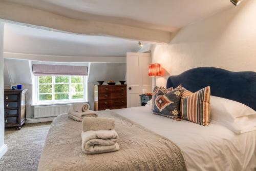 a bedroom with a large bed and a window at Top Cottage, Oddington in Adlestrop