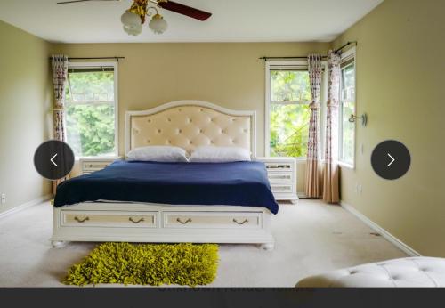 a bedroom with a bed with a blue blanket and two windows at Forest house 4 bedrooms in Surrey