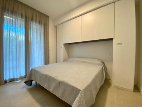 a bedroom with a bed and a large window at Cozy flat 300m from the beach in Bibione