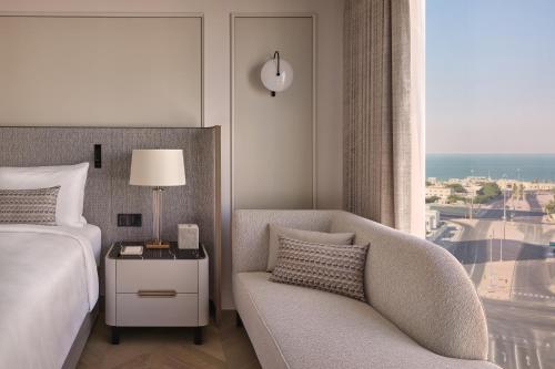 a bedroom with a bed and a chair and a window at JW Marriott Hotel Kuwait in Kuwait