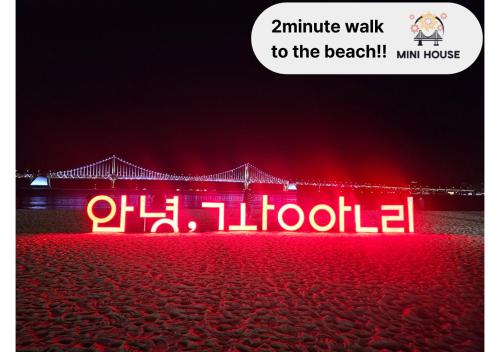 a neon sign on the beach at night at Mini House in Busan