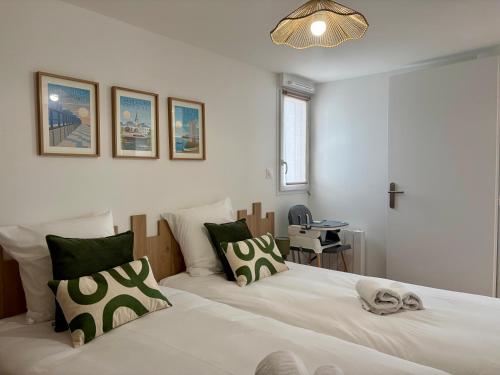a bedroom with two beds with green and white pillows at Les Cabines de la Vie in Saint-Gilles-Croix-de-Vie