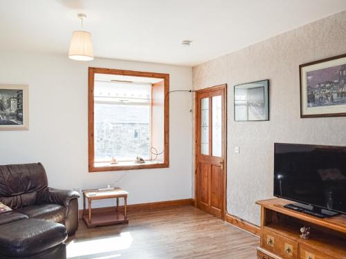 a living room with a couch and a television at Old Barn Cottage - Uk47144 in Glasgow