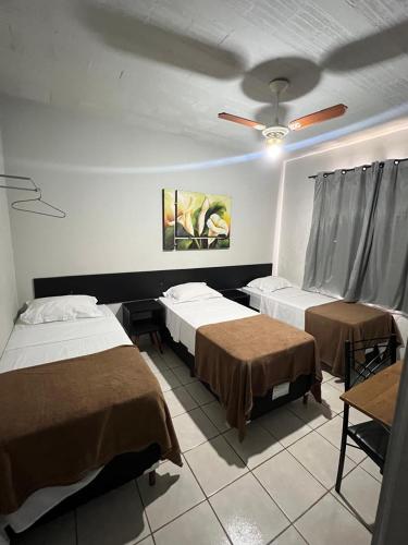 a bedroom with two beds and a ceiling fan at Carmo Palace Hotel in Carmo do Paranaíba