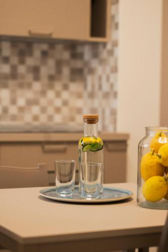 a bottle of lemon juice and two glasses on a table at Zest House Pompei in Pompei