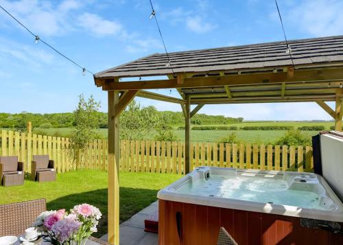 a hot tub under a wooden gazebo at Fairview Lodges in Hollym