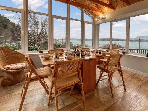 a dining room with a table and chairs and windows at Creag Bheag in Appin