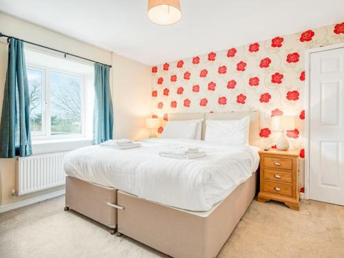 a bedroom with a large bed with red flowers on the wall at Meadow Lakes in St Austell