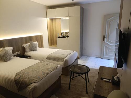 a hotel room with two beds and a table at Tamaya Hotel, Fifth Settlement, New Cairo in Cairo