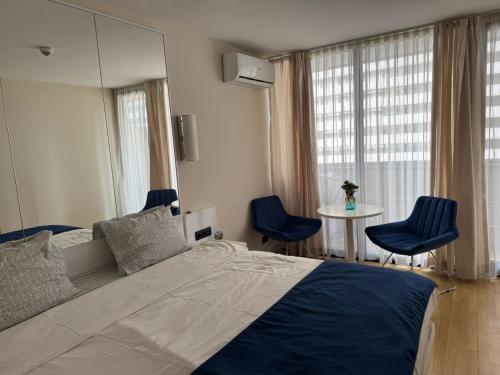 a bedroom with a large bed and two blue chairs at Orbi in Batumi 24 in Angisa