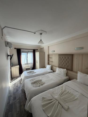 a group of four beds in a room at Akay Hotel in Selçuk
