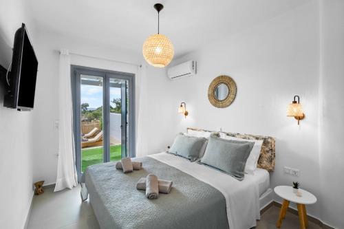 a white bedroom with a bed with two towels on it at Juniper View in Aspro Chorio Paros