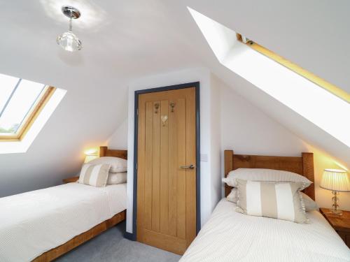 a attic bedroom with two beds and a door at The Croft, Home Farm in Ripley
