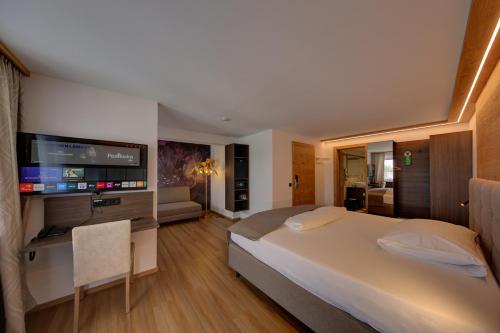 ein Schlafzimmer mit einem großen Bett und einem Flachbildfernseher in der Unterkunft Hotel Leimer Bräu in Lenzing