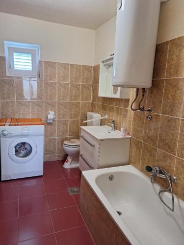 a bathroom with a tub and a toilet and a washing machine at Holiday Home Ružmarin in Velika Čista