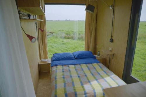 a small bedroom with a bed and a window at De IJsvogel in Wijdewormer