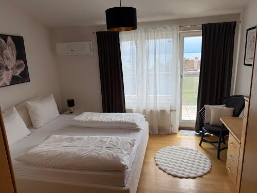a bedroom with a white bed and a large window at Penthouse Seeblick Wohnung 86 qm KLIMATISIERT in Friedrichshafen