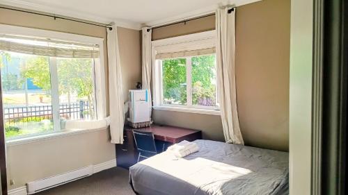 a small bedroom with a bed and two windows at Cold Moon Inn in Nanaimo