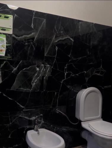 a bathroom with a toilet and a black marble wall at Bovilla Canyon1 in Tirana
