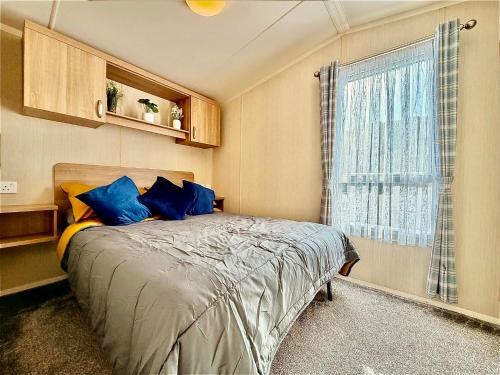a bedroom with a bed with blue pillows and a window at Dale 12 in Burgh Island