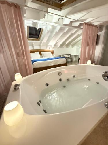 a large white bath tub in a room with a bed at Rebetiko Hotel in Alaçatı