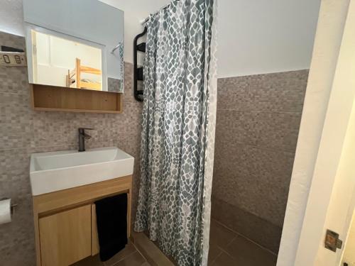 a bathroom with a sink and a shower curtain at Hostel La Bohème in Las Terrenas