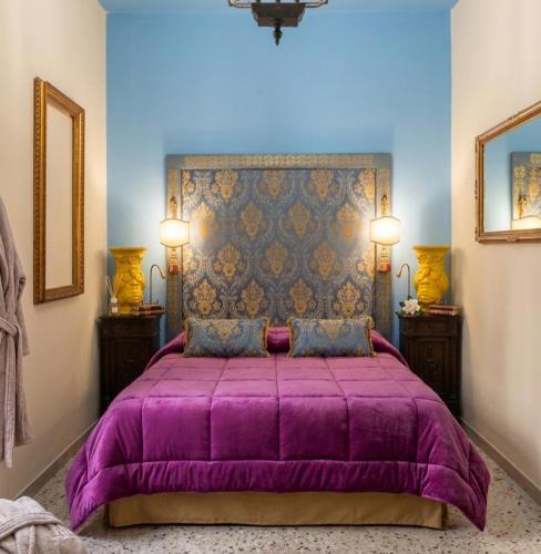 a bedroom with a purple bed with two night stands at Casa d'Artista con Terrazza Panoramica nel Borgo" Ajman house in Sambuca di Sicilia